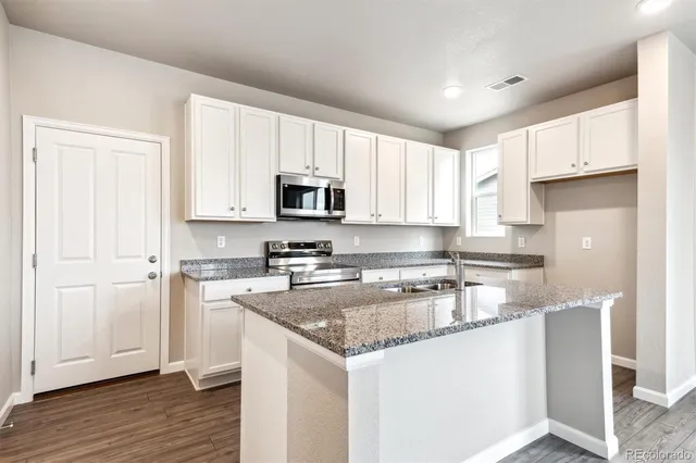 a kitchen with kitchen island granite countertop white cabinets and stainless steel appliances