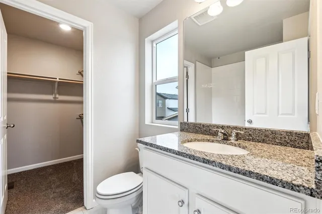 a bathroom with a granite countertop sink mirror vanity and toilet