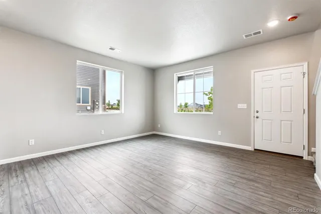 an empty room with wooden floor and windows