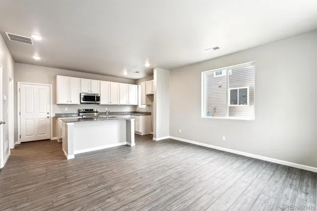 a kitchen with stainless steel appliances white cabinets and wooden floor