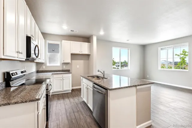 a kitchen with granite countertop stainless steel appliances a stove top oven a sink a counter space and cabinets