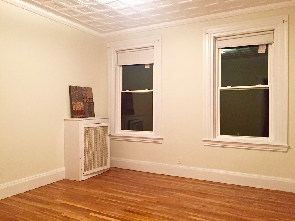 1056 Beacon Street, Unit 15 Brookline, MA 02446 - Photo 6 of 9 a view of an empty room with wooden floor and a window