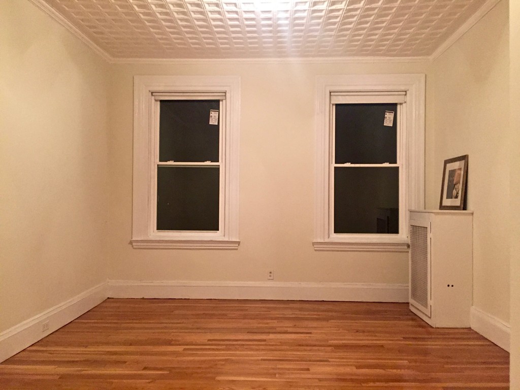 1056 Beacon Street, Unit 15 Brookline, MA 02446 - Photo 7 of 9 an empty room with wooden floor and windows