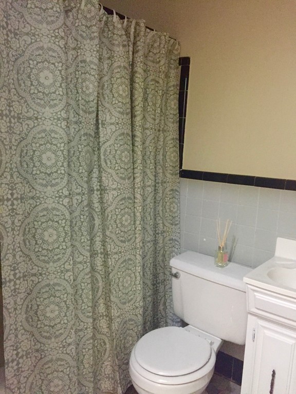 1056 Beacon Street, Unit 15 Brookline, MA 02446 - Photo 9 of 9 a white toilet sitting next to a shower curtain