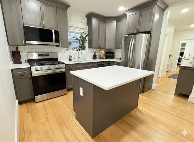 a kitchen with stainless steel appliances a stove a sink a microwave a refrigerator a stove and white cabinets