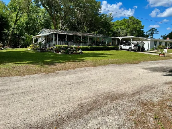 a view of a house with a big yard and large trees