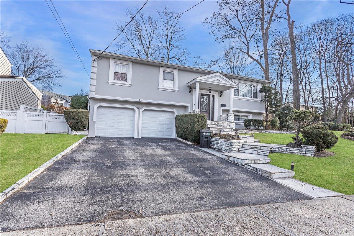 Bi-level home featuring stucco siding, driveway, and a garage