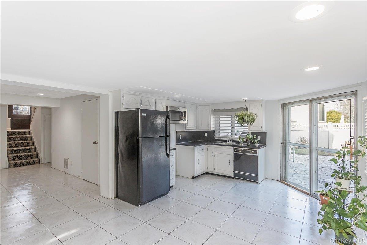 93 Searingtown Road Albertson, NY 11507 - Photo 16 of 24 Kitchen with black appliances, white cabinetry, dark countertops, light tile patterned floors, and recessed lighting
