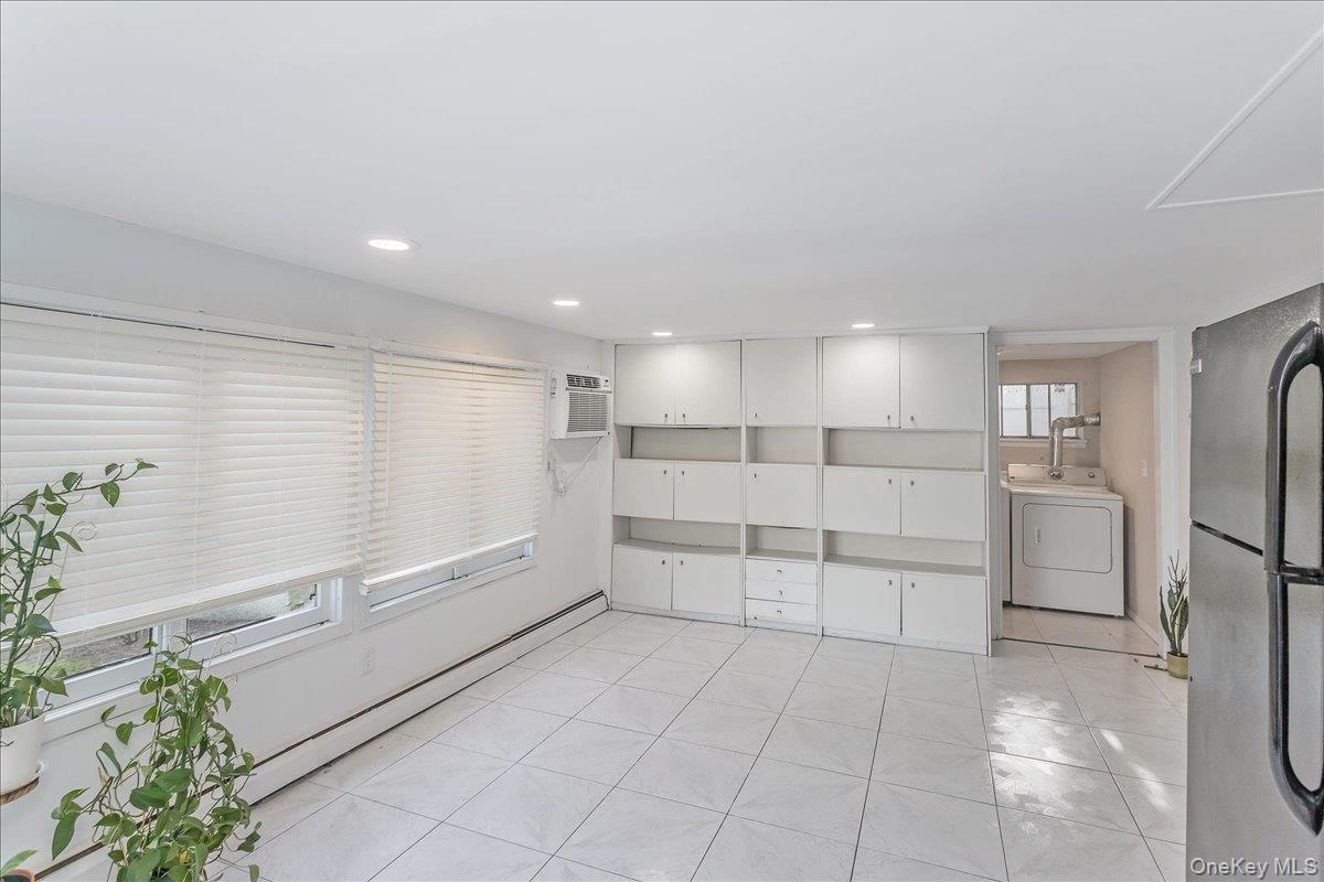 93 Searingtown Road Albertson, NY 11507 - Photo 17 of 24 Spare room featuring washer / dryer, light tile patterned floors, and a baseboard radiator