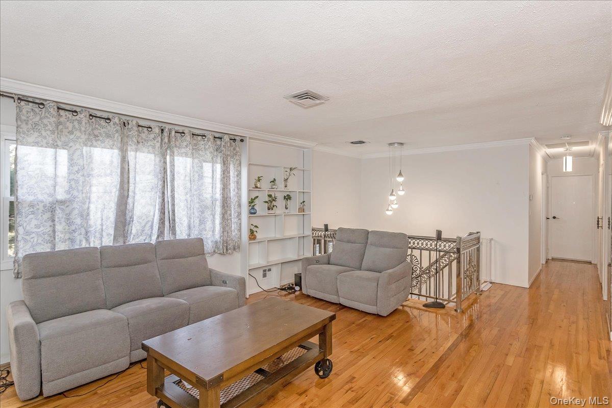 93 Searingtown Road Albertson, NY 11507 - Photo 3 of 24 Living area featuring crown molding, light wood-style flooring, and a textured ceiling