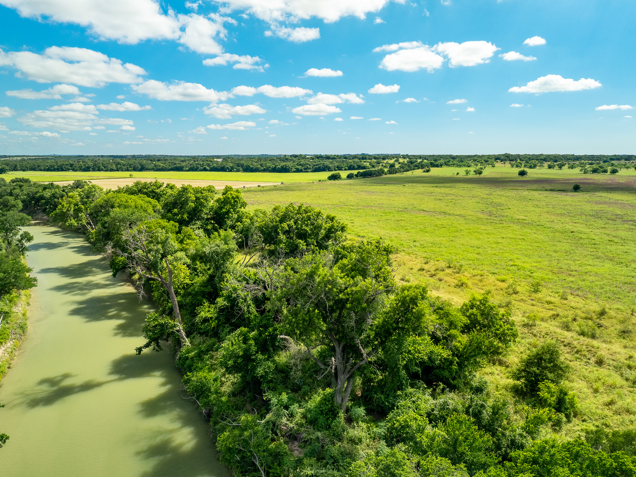 8044 580th Street East Kempner, TX 76539 - Photo 1 of 40 A tranquil river winds through vibrant green fields under an expansive blue sky.