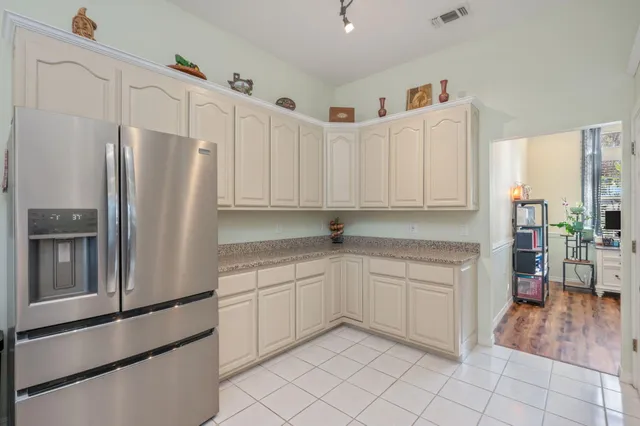 a kitchen with white cabinets and refrigerator