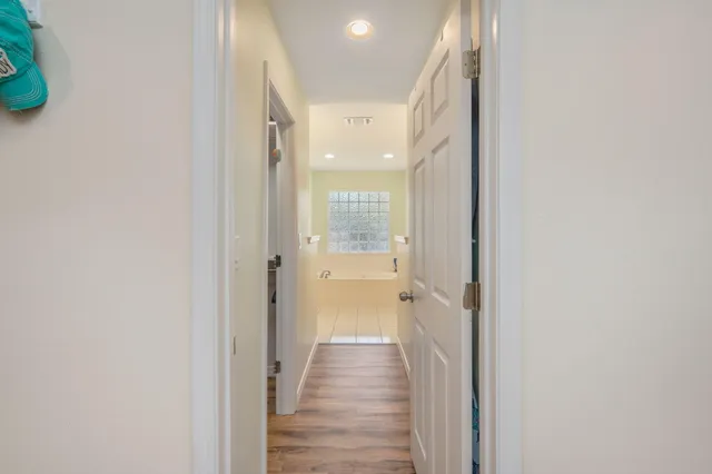 a view of a hallway with wooden floor and a bathroom