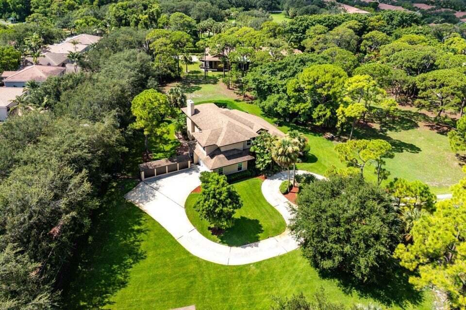 an aerial view of a house with a yard and trees all around