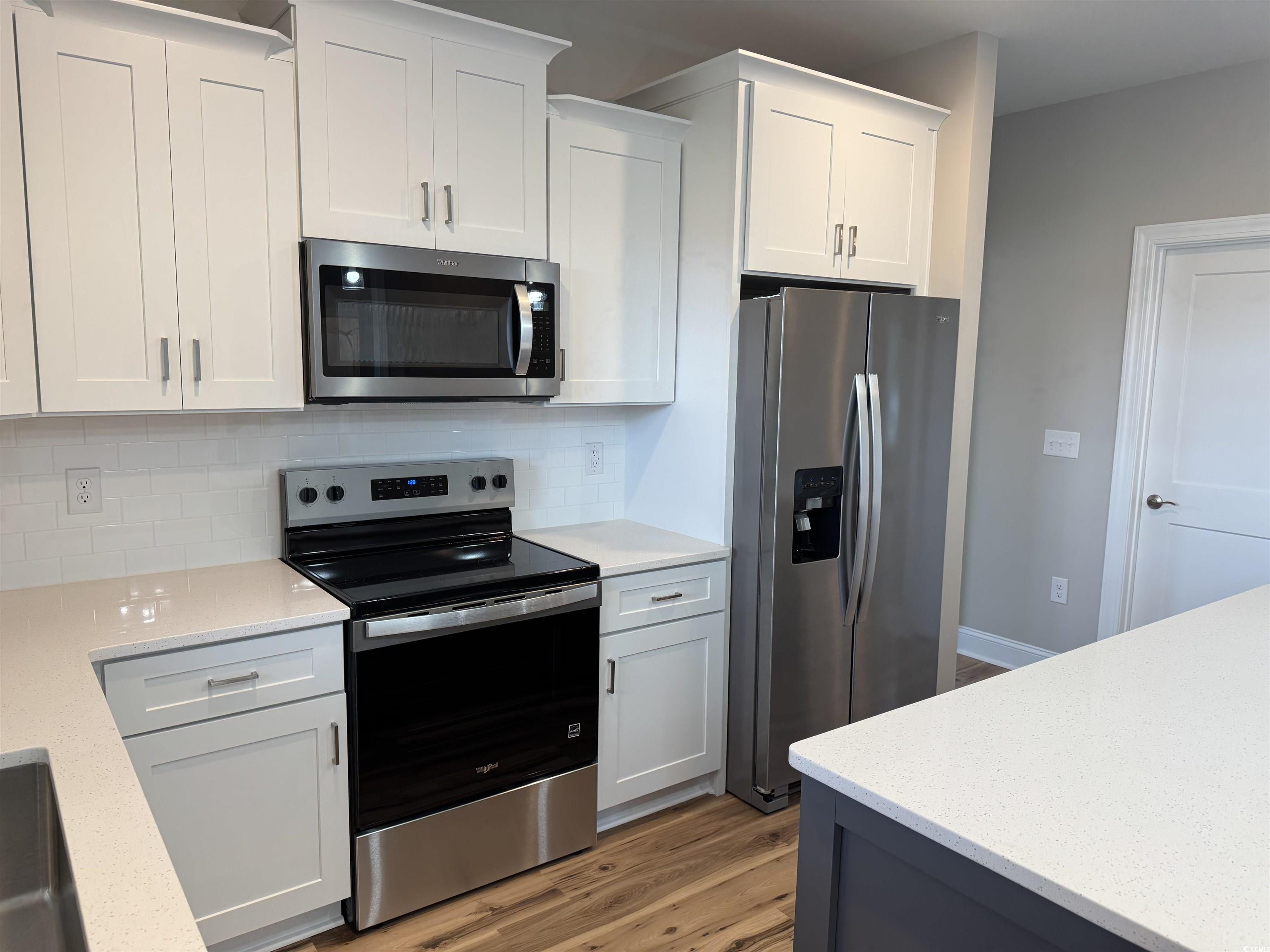 4963 Dupont Road Aynor, SC 29511 - Photo 5 of 18 Kitchen with stainless steel appliances, light wood-style floors, white cabinets, and light stone countertops