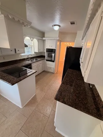 a kitchen with granite countertop a sink and white cabinets