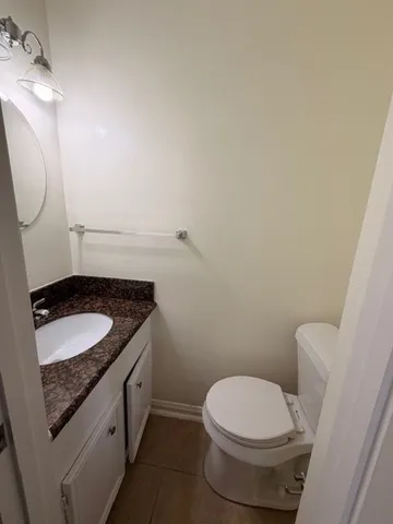 a bathroom with a granite countertop toilet and a sink