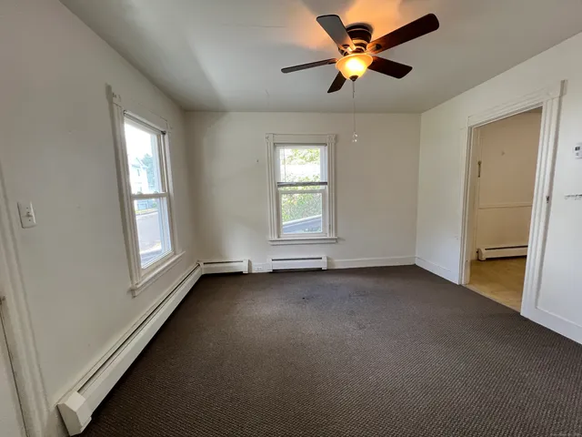 a view of an empty room with window and chandelier fan
