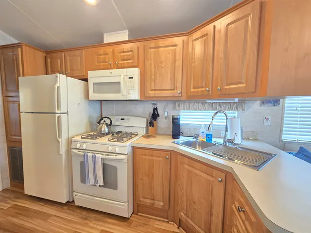 a utility room with stainless steel appliances granite countertop a refrigerator a sink a stove a washer and dryer with wooden floors