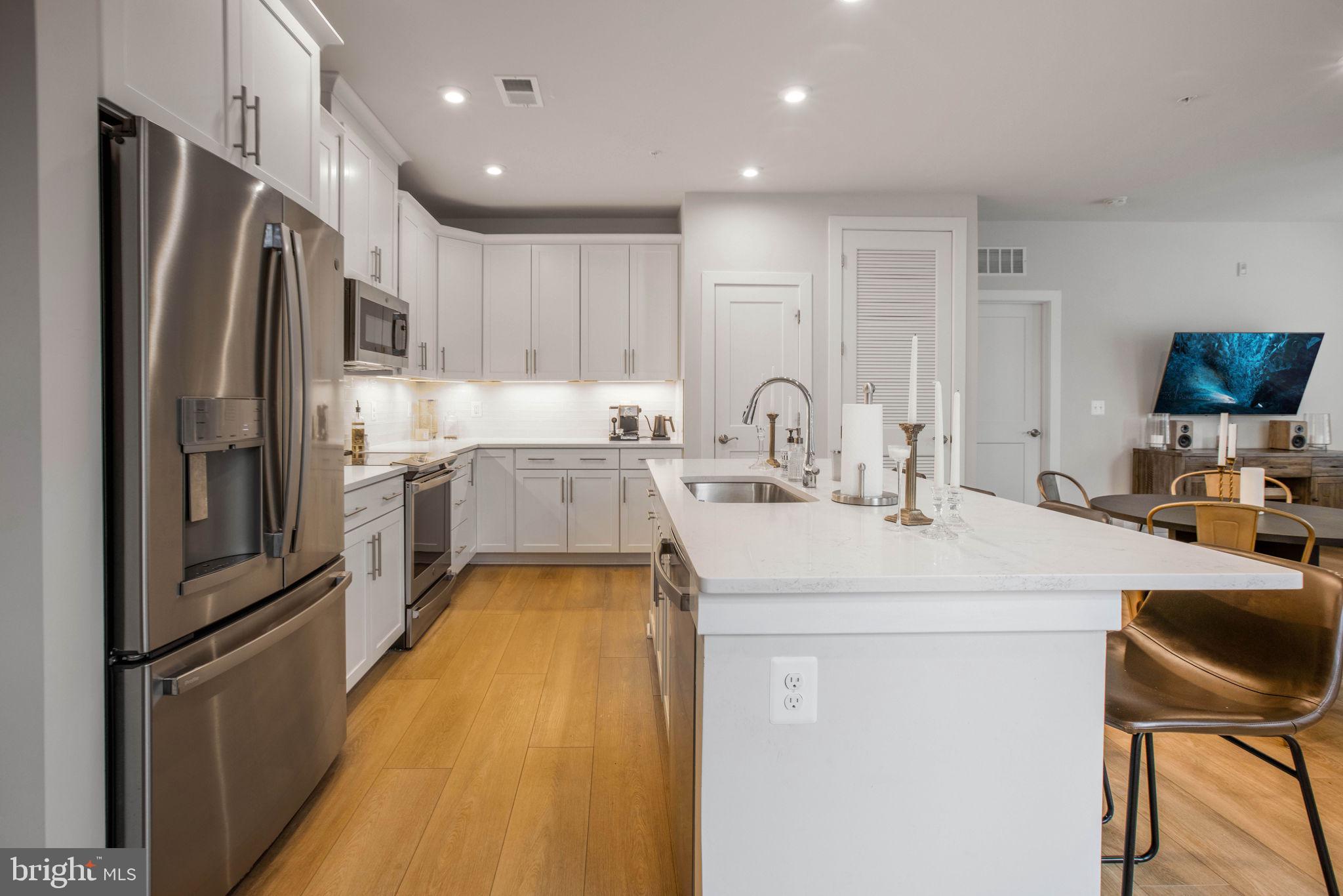 1669 Bandit Loop, Unit 107A Reston, VA 20190 - Photo 2 of 30 a kitchen with kitchen island a counter top space a sink stainless steel appliances and cabinets