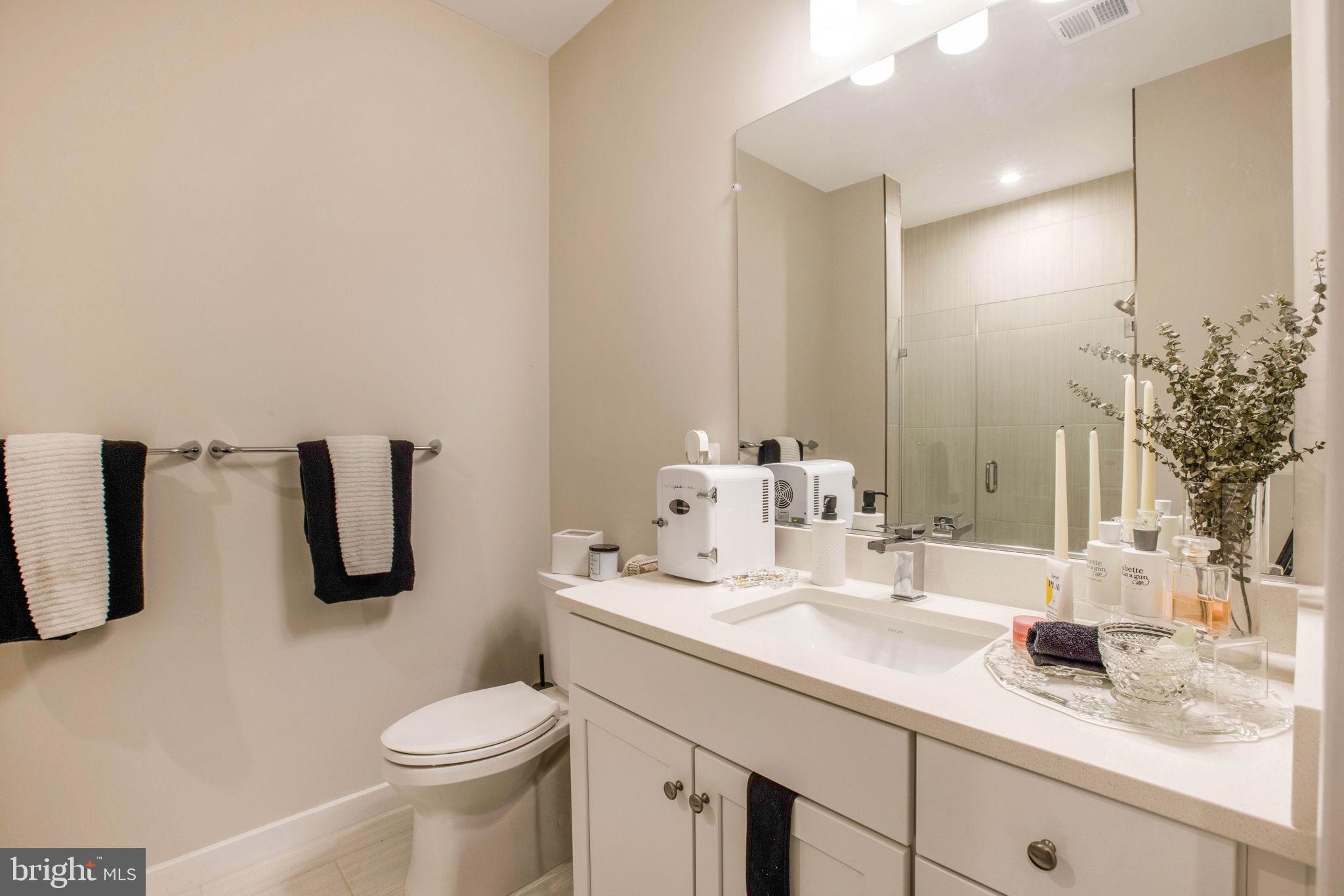 1669 Bandit Loop, Unit 107A Reston, VA 20190 - Photo 26 of 30 a bathroom with a granite countertop sink a toilet and mirror