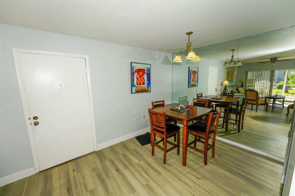 3251 South Beneva Road, Unit 101 Sarasota, FL 34232 - Photo 11 of 22 a dining room with wooden floor a chandelier a wooden table and chairs