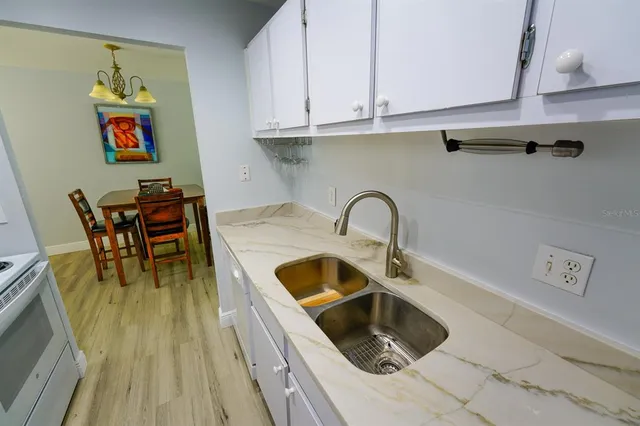 a kitchen with a sink and a stove with wooden floor