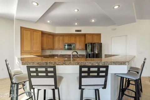 a kitchen with granite countertop a table chairs microwave and cabinets