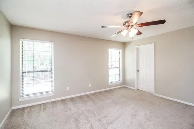 an empty room with windows and fan