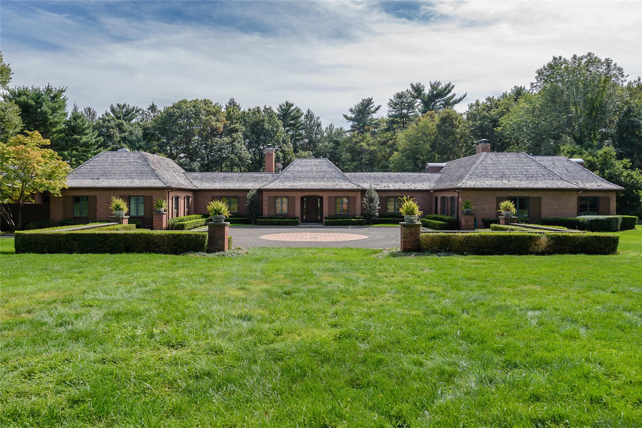 Rear view of property with a chimney, a high end roof, and brick siding