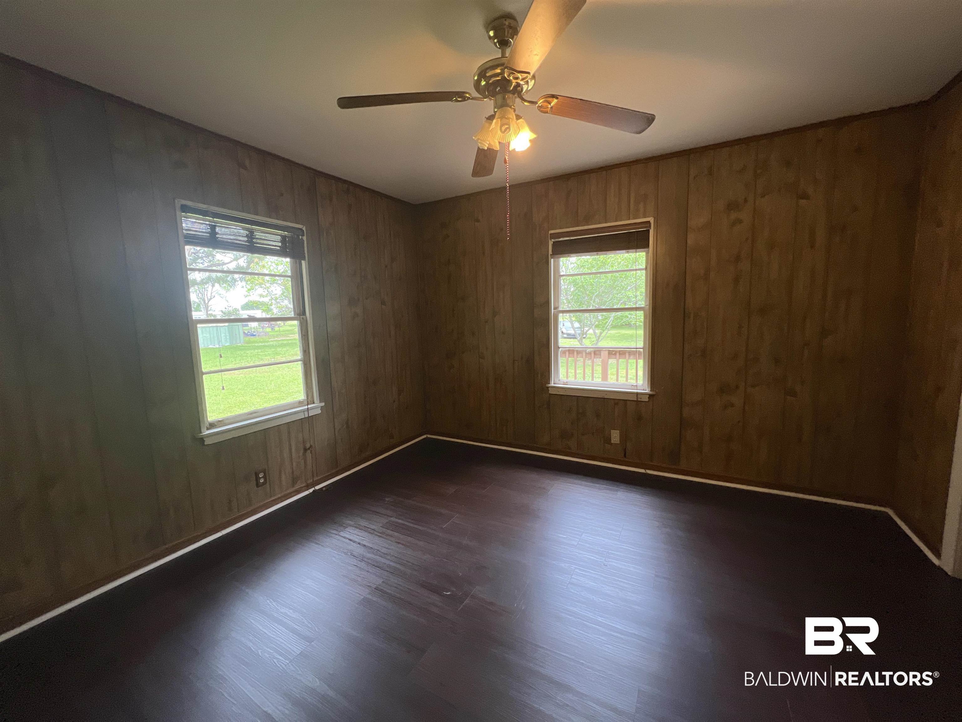 13301 A Hugh Fort Road Grand Bay, AL 36541 - Photo 12 of 34 Unfurnished room featuring dark wood finished floors, healthy amount of natural light, ceiling fan, and wood walls