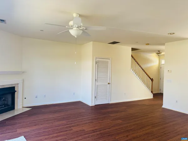 a view of an empty room with wooden floor and a fireplace