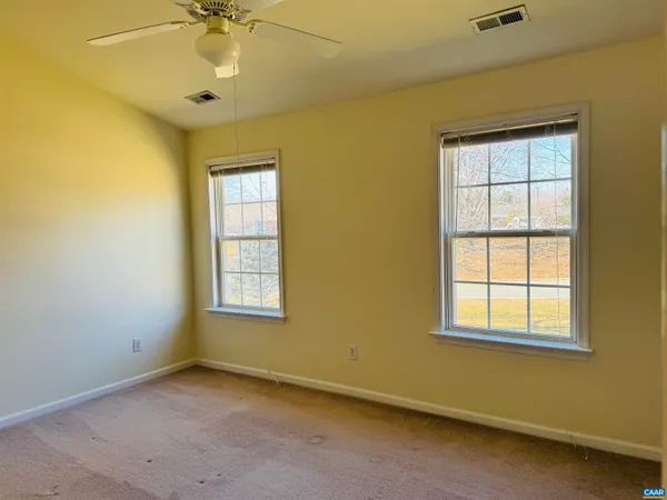 an empty room with a window and ceiling fan