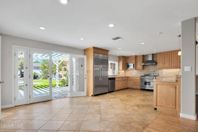 a kitchen with stainless steel appliances granite countertop a refrigerator and a stove top oven