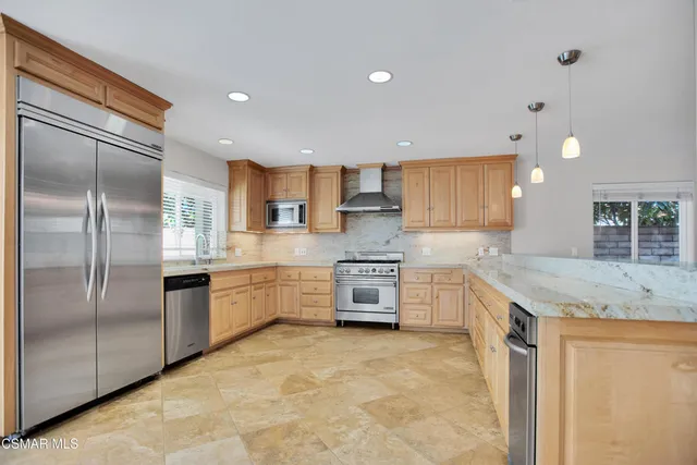 a large kitchen with stainless steel appliances granite countertop a stove a sink and a refrigerator
