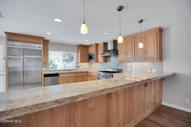 a kitchen with stainless steel appliances granite countertop a sink a stove and a wooden floors