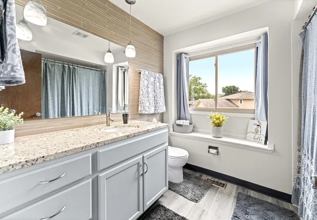 a bathroom with a granite countertop sink toilet a large mirror a bathtub and window