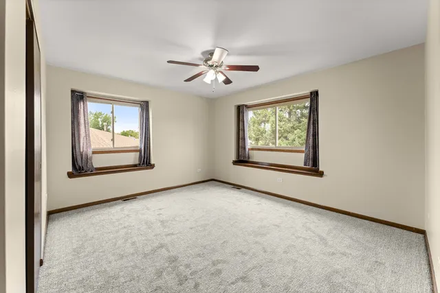 an empty room with windows and ceiling fan view