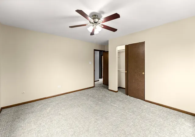 an empty room with closet and ceiling fan