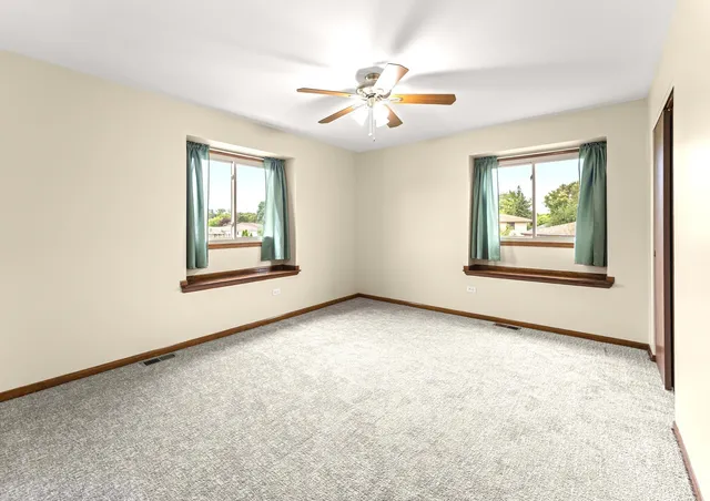 an empty room with windows and ceiling fan
