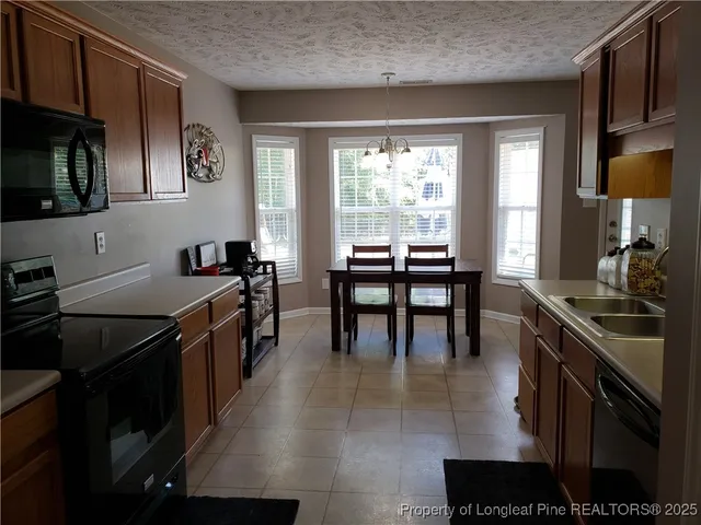 a kitchen with granite countertop a stove a sink a dining table and chairs