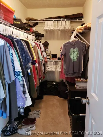 a view of walk in closet with clothes and shoes