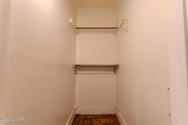 a view of an empty room with wooden floor fireplace and a window