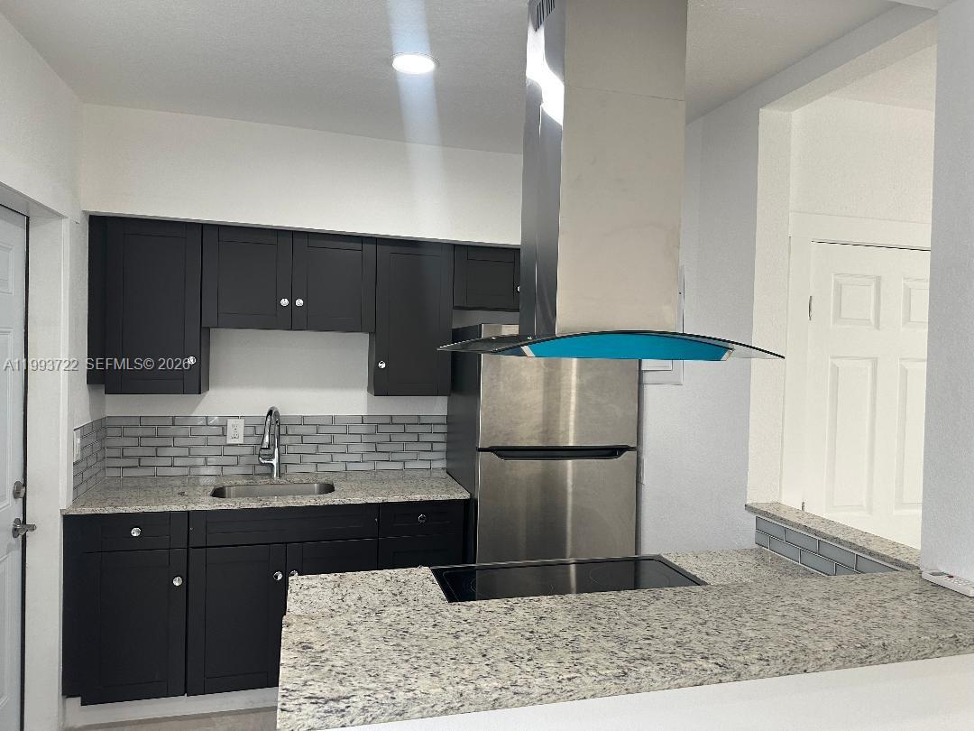 7115 Rue Granville, Unit D Miami Beach, FL 33141 - Photo 4 of 13 a kitchen with stainless steel appliances kitchen island granite countertop a refrigerator and a sink