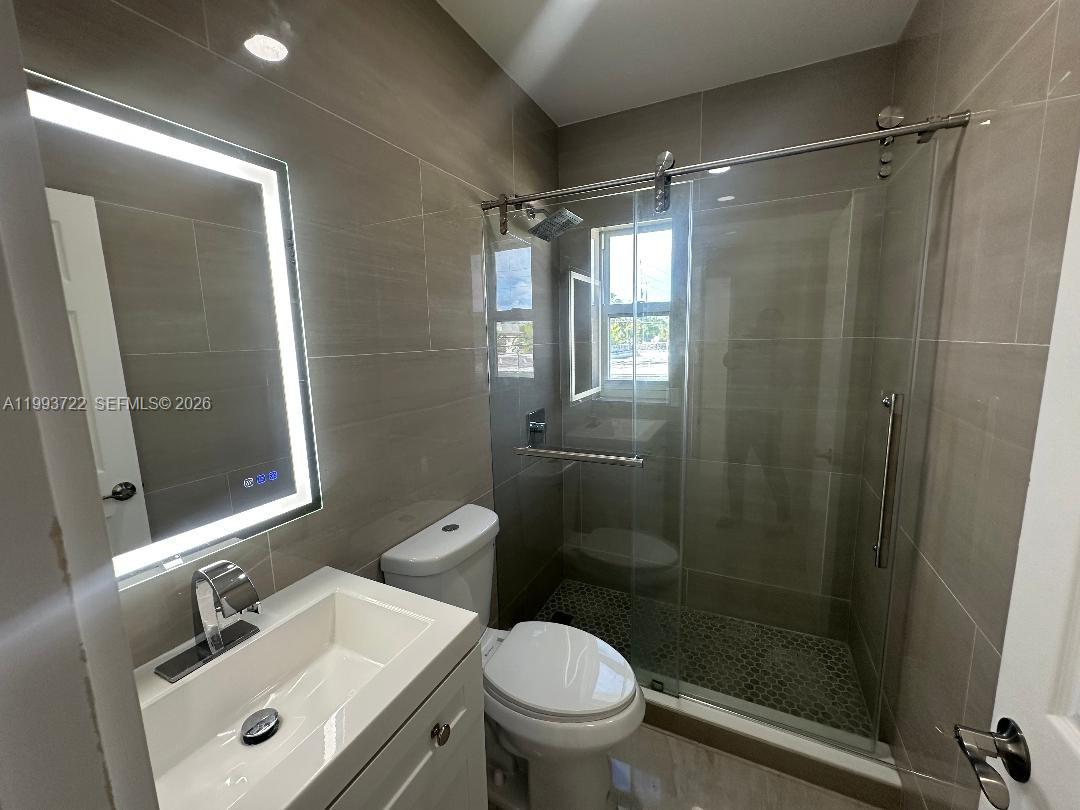 7115 Rue Granville, Unit D Miami Beach, FL 33141 - Photo 10 of 13 a bathroom with a sink mirror toilet and shower