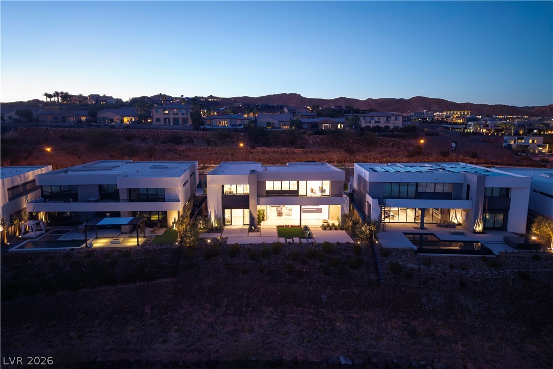 25 Falling Ridge Lane Henderson, NV 89011 - Photo 33 of 48 Illuminated luxury homes nestled in a vibrant community with mountainous views at dusk.