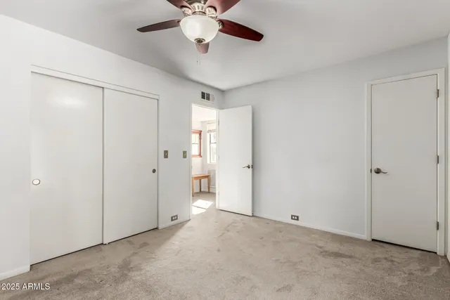 an empty room with a chandelier fan and windows