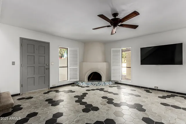 a view of a livingroom with a fireplace a ceiling fan and wooden floor