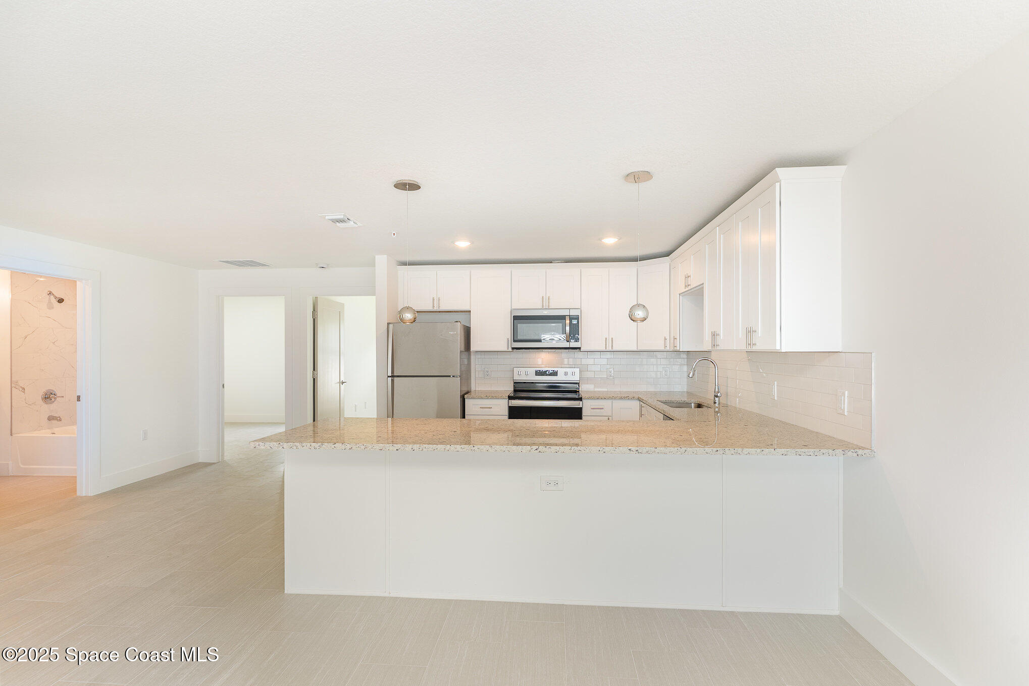 1635 Par Street Northeast, Unit 2202 Palm Bay, FL 32905 - Photo 8 of 45 a large white kitchen with kitchen island a stove a sink a refrigerator and white cabinets