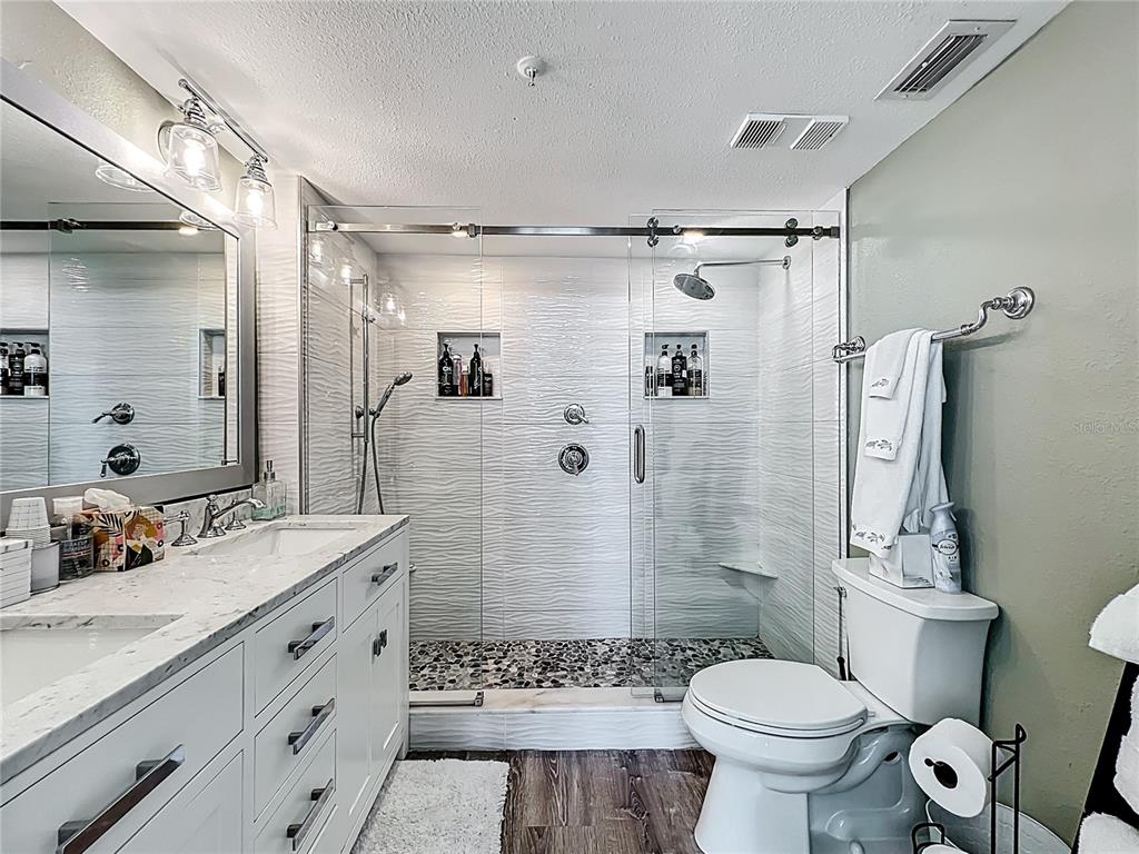 14146 Gulf Boulevard, Unit 3A Madeira Beach, FL 33708 - Photo 18 of 29 a bathroom with a double vanity sink toilet mirror and shower